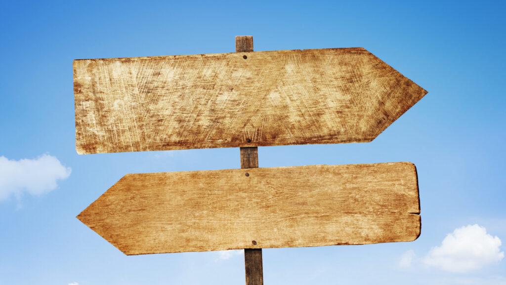 Placa com duas setas opostas, representando a escolha estratégica entre um BPO de CX e um time de atendimento interno.